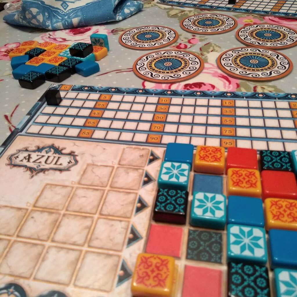 Tiles in rows on a game board there are circular tiles in the background and more tiles. The game is Azul