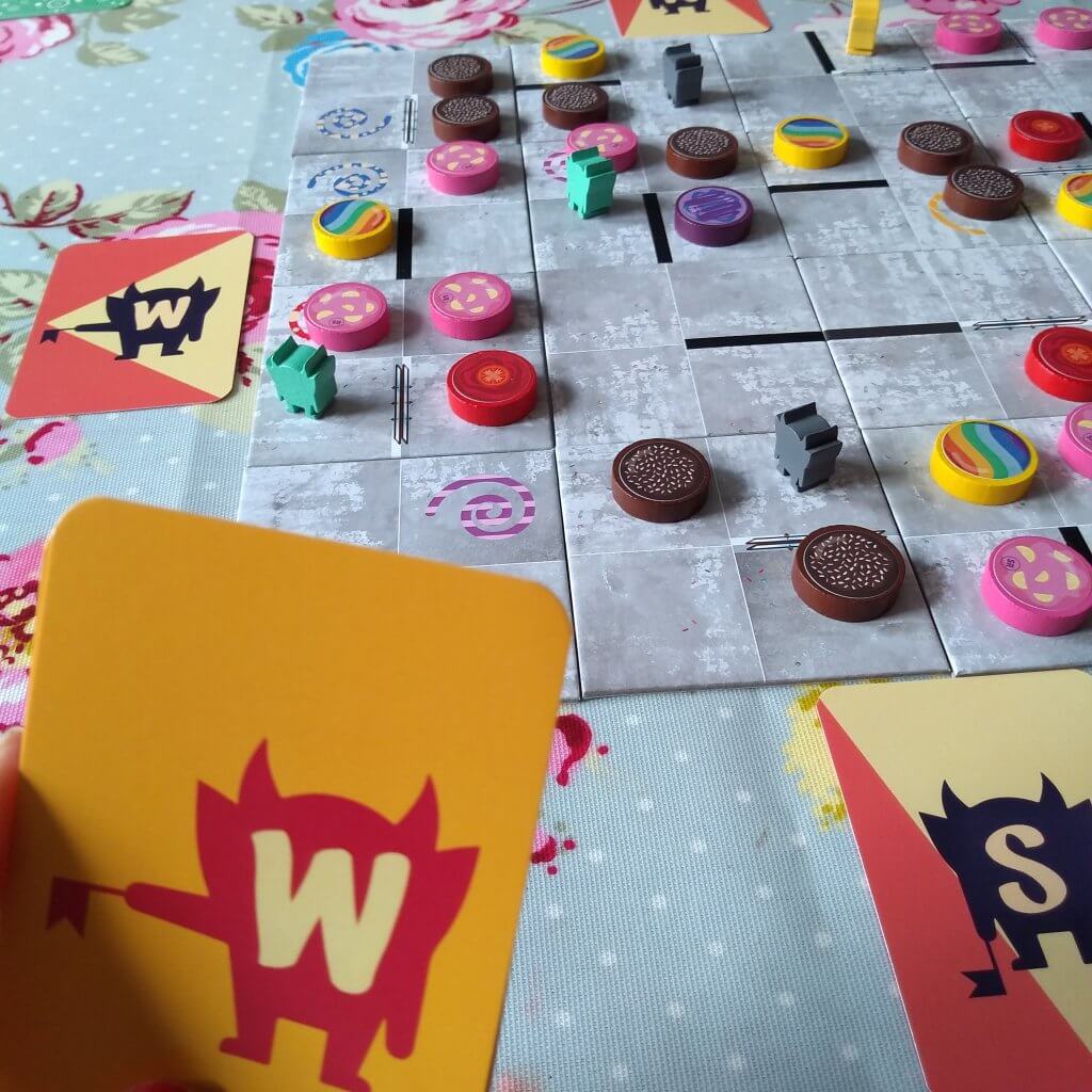 Doughnut Dash game. Square tiles that form the board with small wooden doughnut pieces on. Cards with directions on (North South East West)