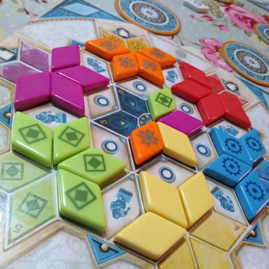 Azul Summer palace. Tiles have been placed on a board on top of their matching colour to form star shapes. There are some empty spaces. 